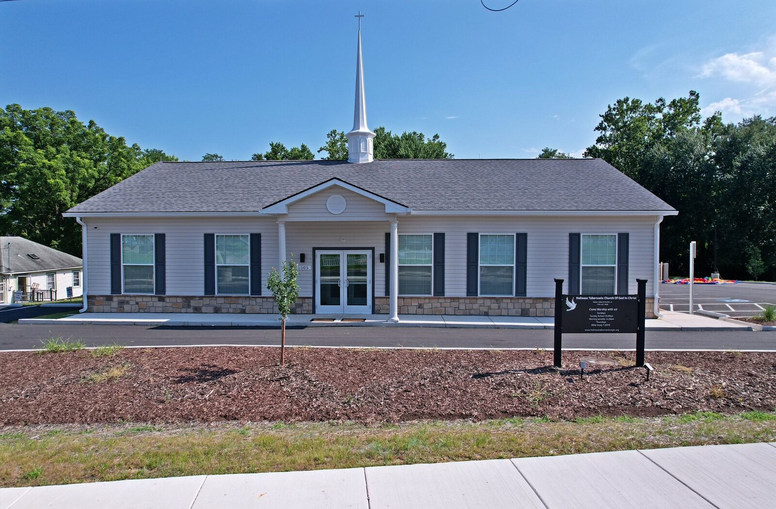 The new Holiness Tabernacle COGIC church building with white steeple and cross at 1505 Walnut Street, Woodbridge, VA
